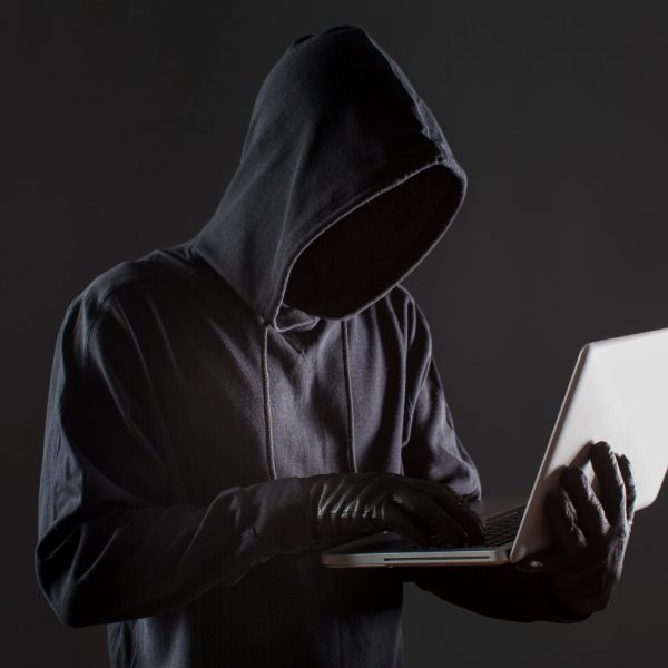 side-view-of-male-hacker-with-gloves-and-laptop